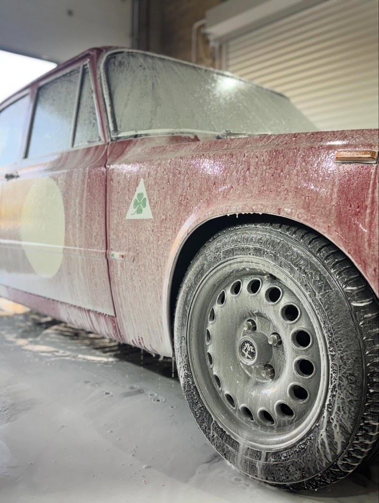 Classic red Alfa Romeo covered in snow foam during the wash